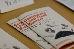 Photo of conference pamphlet that reads "Community Land Trust Summit"